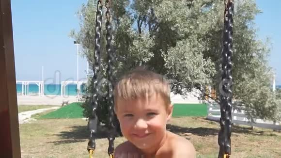 小男孩在海边的绳索秋千上玩得很开心视频的预览图