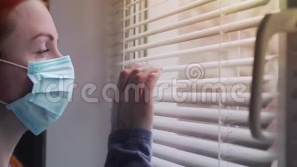 一个戴防护面罩的女人看着窗外视频的预览图