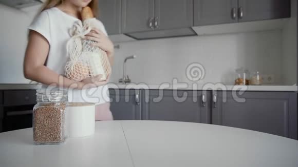 女人在木桌上打开厨房里的面包牛奶和橘子的购物袋零废物之家和生态袋视频的预览图