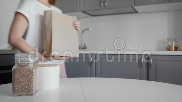 女人在木桌上打开厨房里的面包牛奶和橘子的购物袋零废物之家和生态袋视频的预览图