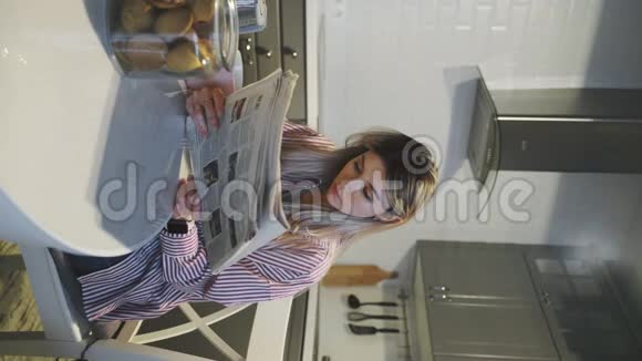 一个年轻漂亮的黑发女人头发松松戴眼镜在家喝咖啡看报纸视频的预览图