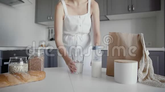 无法辨认的女人穿着白色连衣裙在餐桌上喝着牛奶玻璃视频的预览图