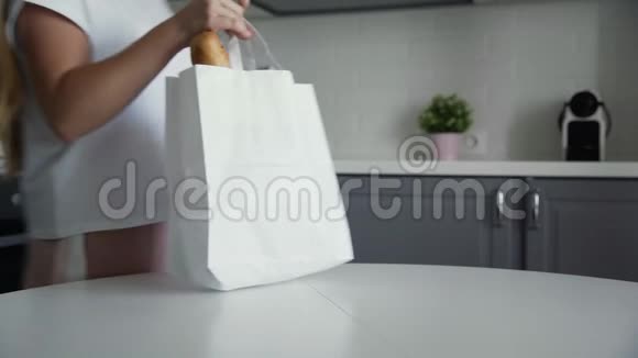 女人在木制桌子上打开厨房里的面包燕麦片牛奶蔬菜的购物袋零垃圾家庭和视频的预览图