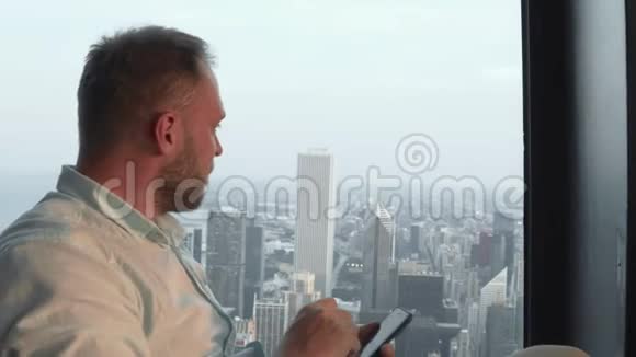 年轻英俊的男人在智能手机上拍照从摩天大楼拍摄美国芝加哥的全景视频的预览图