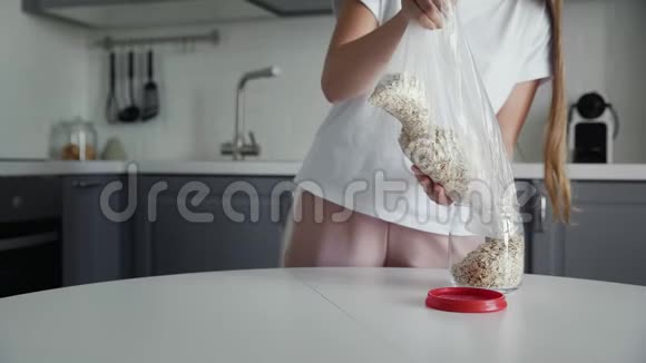 女人把燕麦片倒入一个玻璃罐子里储存视频的预览图