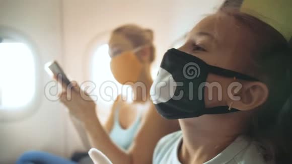 家庭妇女和儿童婴儿旅行旅游白种人在飞机上戴着防护医疗面罩使用视频的预览图