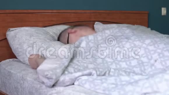 年轻人戴着睡眠面具睡不着一个人躺在房间的床上患有失眠症视频的预览图