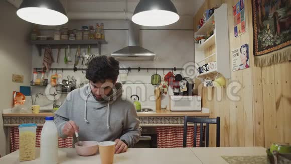 一个在厨房吃早餐的年轻人男人吃玉米片视频的预览图