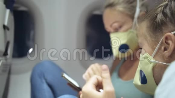 家庭妇女和儿童婴儿旅行旅游白种人在飞机上戴着防护医疗面罩使用视频的预览图