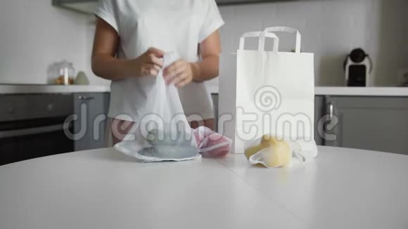 年轻女子在木桌上的厨房里用蔬菜包装购物袋零废家和生态袋生态视频的预览图
