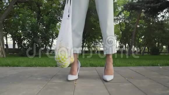 无法辨认的女人拿着带水果的棉网购物袋在夏天的公园里摆姿势拍照视频的预览图