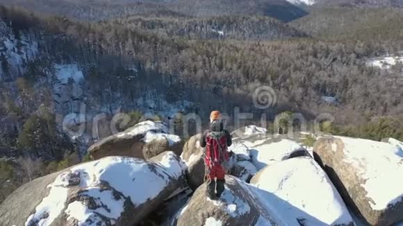 一个孤独的雄性登山者在雪山山顶上的鸟瞰视频的预览图