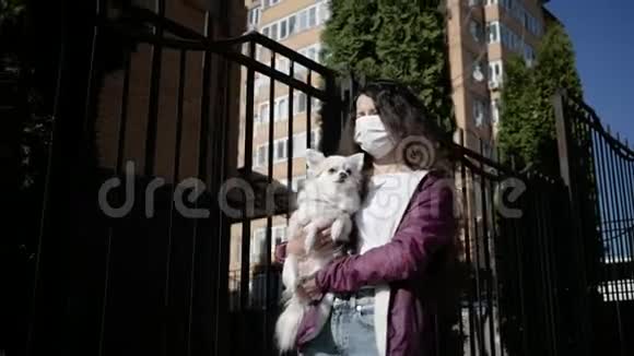 戴防护面罩的女人独自在户外和狗一起散步因为冠状病毒流行视频的预览图