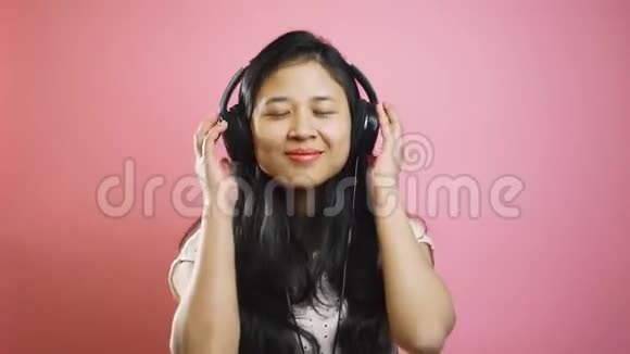 快乐无忧无虑的亚洲女孩用耳机听音乐微笑和跳舞视频的预览图