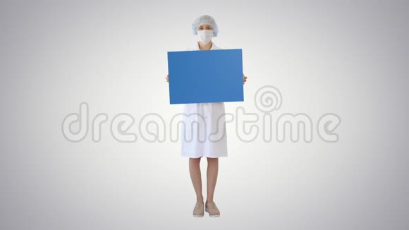 年轻的女医生戴着面具在梯度背景上拿着一个空的账单板视频的预览图