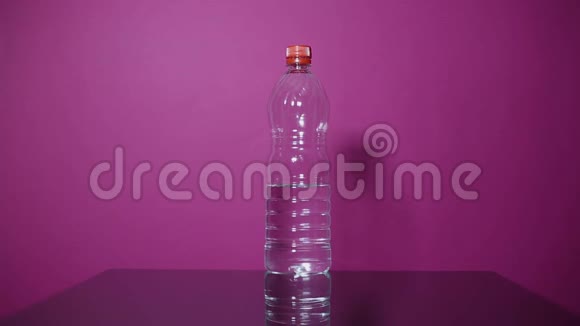 年轻人把塑料瓶换成玻璃桌上的钢制热水瓶背景是粉红色视频的预览图