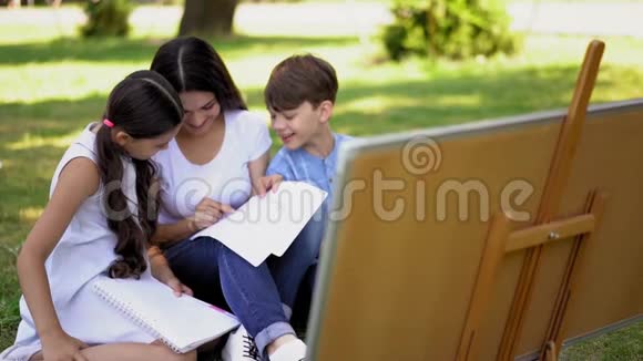妈妈帮助她的孩子在公园里做学校工作视频的预览图