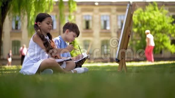 孩子们坐在绿草上画画视频的预览图