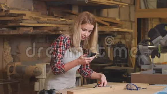 专心致志的木匠女人带着手机视频的预览图