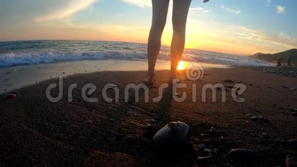 年轻女子奔跑着手举在金色的夕阳背景下的沙滩上视频的预览图