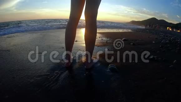 金色夕阳背景下的年轻女子沿着沙滩海浪奔跑视频的预览图