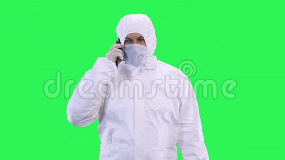 一个穿着防护服戴着防护面罩和眼镜的人正在打电话视频的预览图