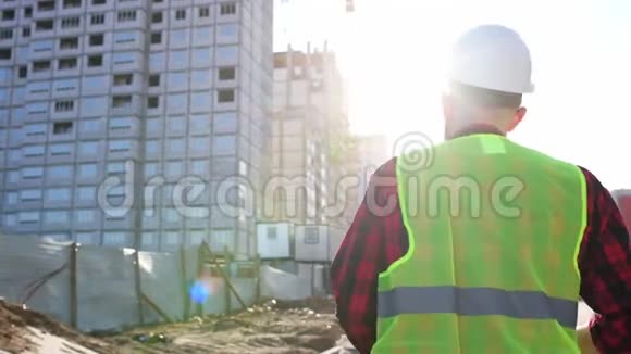 继职业工人戴着安全帽拍摄蓝图走过现代建筑工地视频的预览图