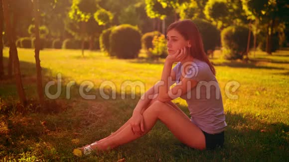忧郁的女人坐在绿草上视频的预览图
