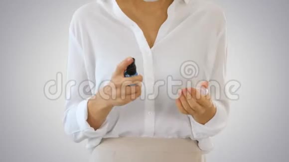 年轻女子使用皮肤消毒器保护她的手免受任何病毒同时行走在梯度背景视频的预览图