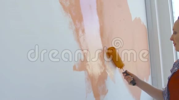 单身生活方式概念年轻快乐的女人用滚筒把墙壁涂成橙色视频的预览图