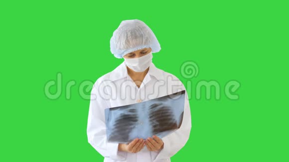 女医生戴着医疗面具看着绿色屏幕上的x射线图像Chroma键视频的预览图