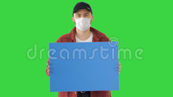 成熟的男性农民在医疗面具持有空白标牌在绿色屏幕铬键视频的预览图