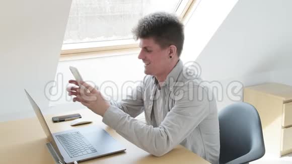 在笔记本电脑上笑快乐的男人拿着智能手机把它放在一边然后回去工作视频的预览图