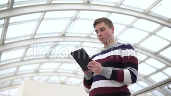 一个年轻人拿着一块石碑站着一个人用平板电脑抵住玻璃屋顶一个忙碌的人正在发短信视频的预览图