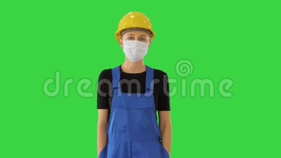 年轻女子穿着黄色硬帽戴着医用面具走在绿色屏幕上Chroma键视频的预览图