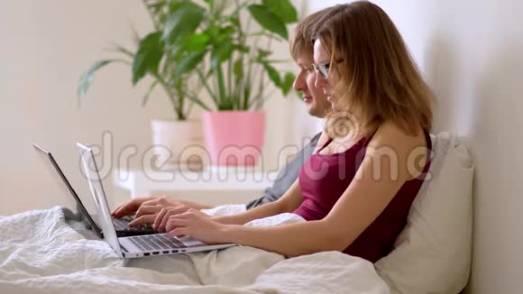 一个男人和女人在卧室里用笔记本电脑工作视频的预览图