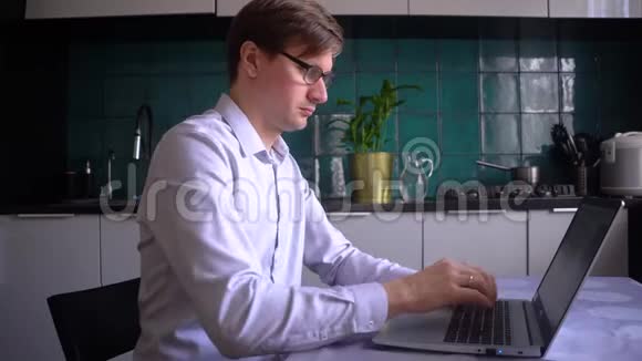 一个男人在厨房里用笔记本电脑工作他的孩子在家里有儿子的父亲视频的预览图