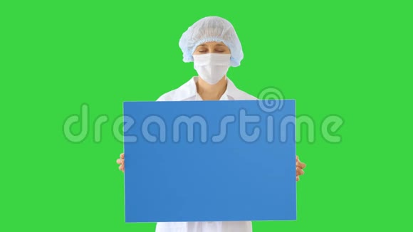 戴着面具的女医生在绿色屏幕上举着一块空板Chroma键视频的预览图