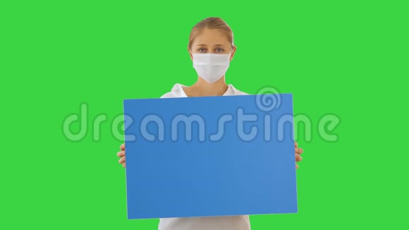 漂亮的女商人戴着保护面具在绿色屏幕上拿着空白板Chroma键视频的预览图