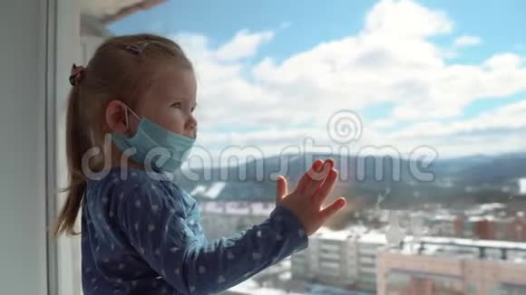 一个戴着医用口罩的小女孩在一次世界性的病毒流行中从窗户往外看停止感染流感及SARS视频的预览图