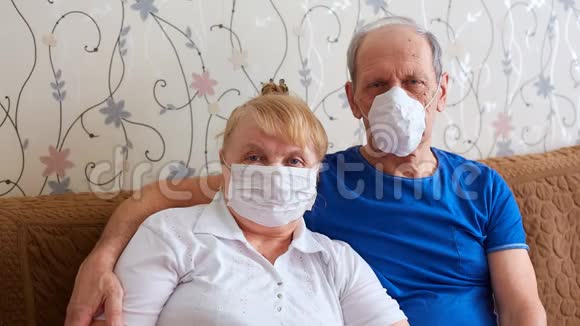 老年夫妇戴着医用口罩在流行病期间为老年人提供自我隔离模式视频的预览图