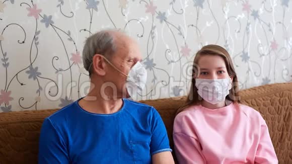 祖父和孙女戴着医疗面具被隔离流行病期间的自我孤立视频的预览图