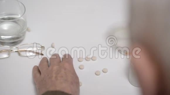 老人从房间的桌子上拿出白色的药丸和水视频的预览图