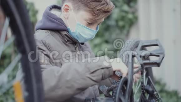 一个十几岁的孩子正在用医用口罩修理他的自行车视频的预览图