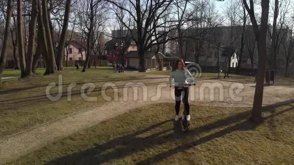 长发女孩骑着黑色电动滑板车在公园里视频的预览图