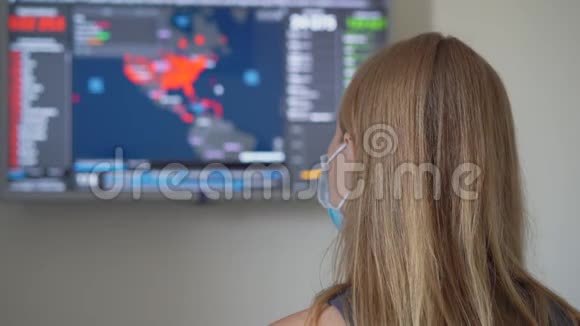 一位戴着医用口罩的年轻女子看着屏幕屏幕上有多少人感染了covid19视频的预览图