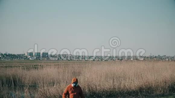 一个穿着防护服戴着呼吸器的人在远处的一个小城市背景下视频的预览图