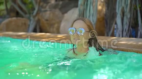 一位年轻女子在热带度假胜地有温泉瀑布和游泳池有热水慢动作视频的预览图