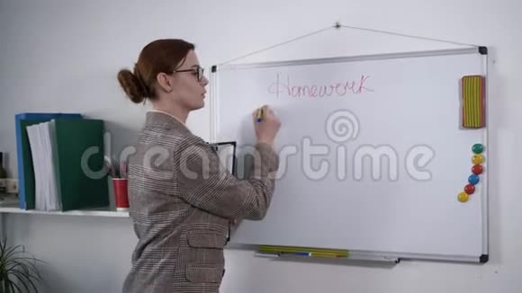 年轻的女数学老师带着视力眼镜在学校里用记号笔在磁性黑板上写下一个方程式视频的预览图