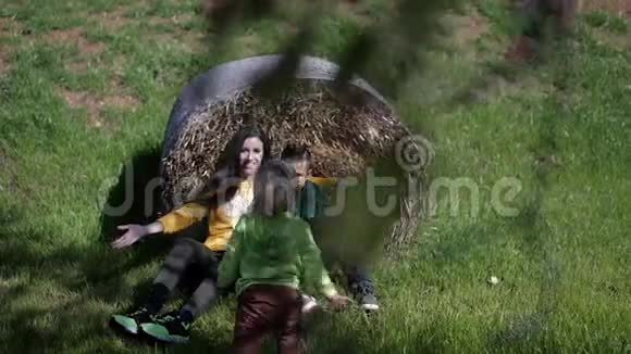 年轻的家庭母亲和两个儿子在草地和干草的背景下拥抱视频的预览图